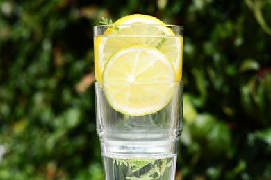 Photo of Delicious refreshing lemonade against green blurred background, closeup