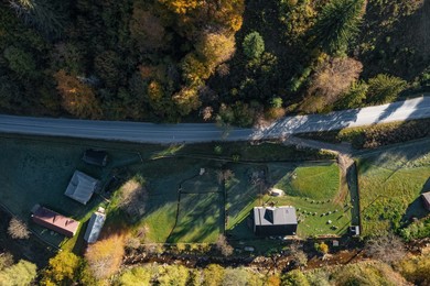 Image of Aerial view of farm and road near beautiful autumn forest