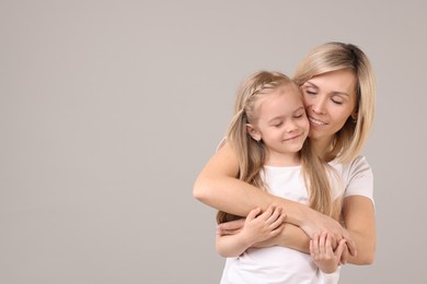 Family portrait of happy mother and daughter on grey background. Space for text