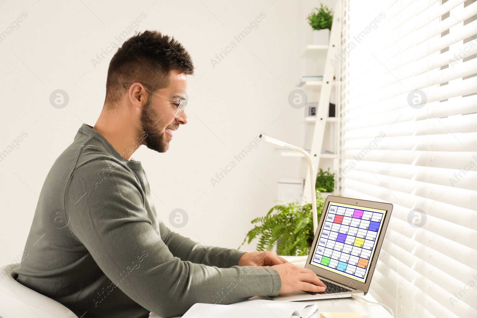 Photo of Young man using calendar app on laptop in office