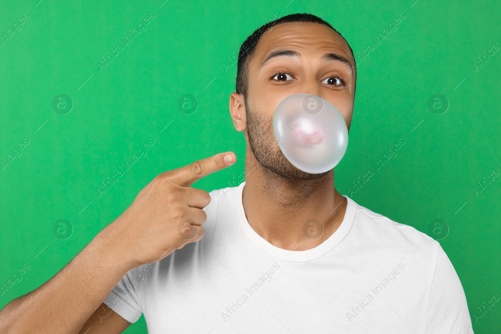 Photo of Portrait of man blowing bubble gum on green background