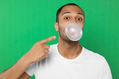 Portrait of man blowing bubble gum on green background