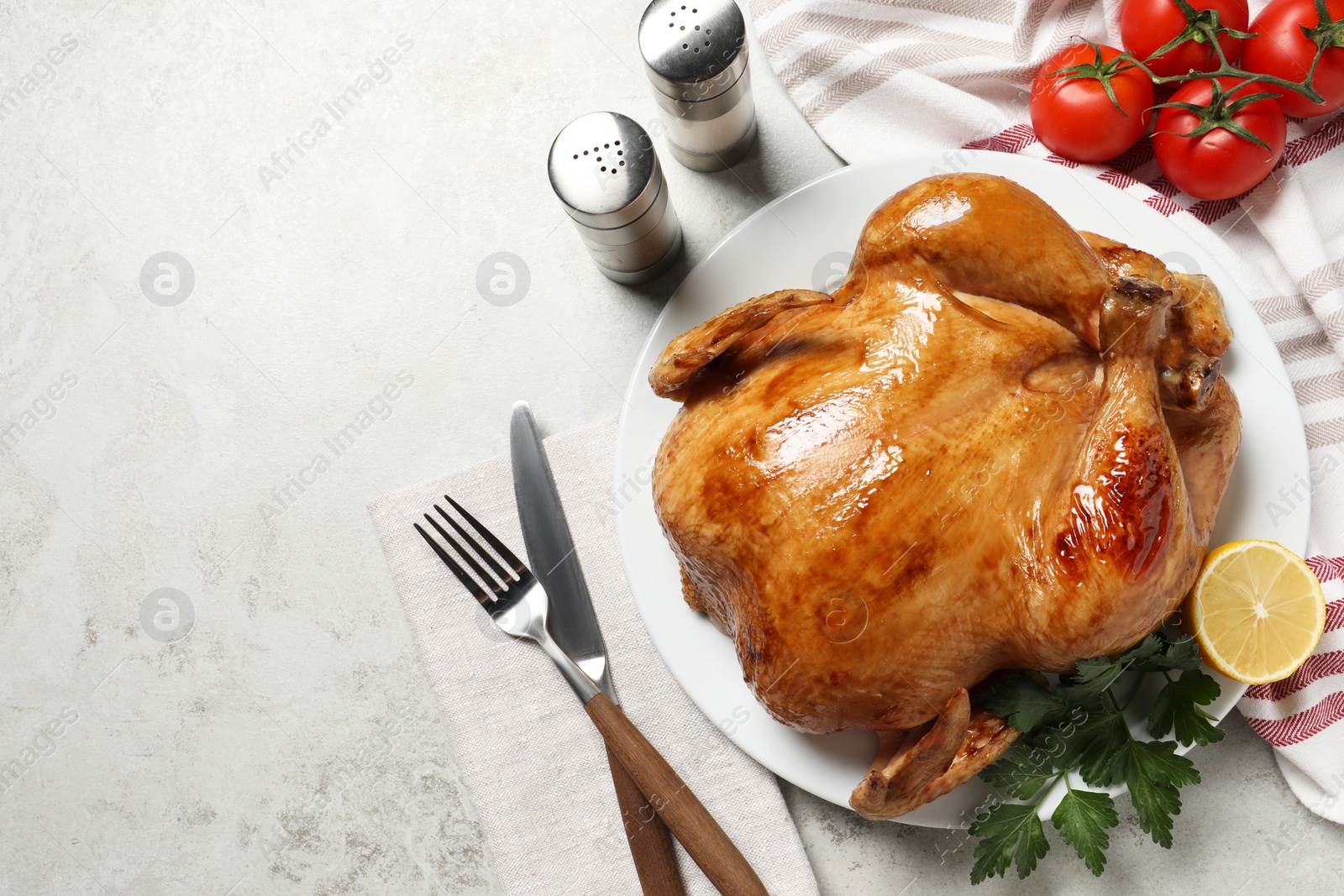 Photo of Tasty roasted chicken with parsley and lemon served on light grey table, flat lay. Space for text