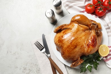 Photo of Tasty roasted chicken with parsley and lemon served on light grey table, flat lay. Space for text