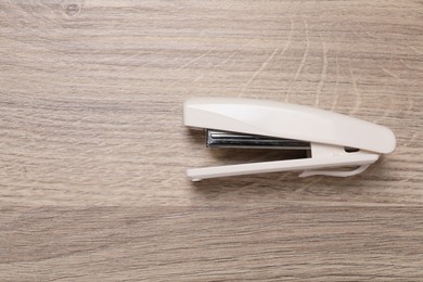 Photo of One beige stapler on wooden table, top view. Space for text