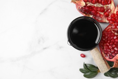 Photo of Tasty pomegranate sauce, fruits and branch on white marble table, flat lay. Space for text