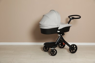 Photo of Baby carriage. Modern pram near beige wall, space for text