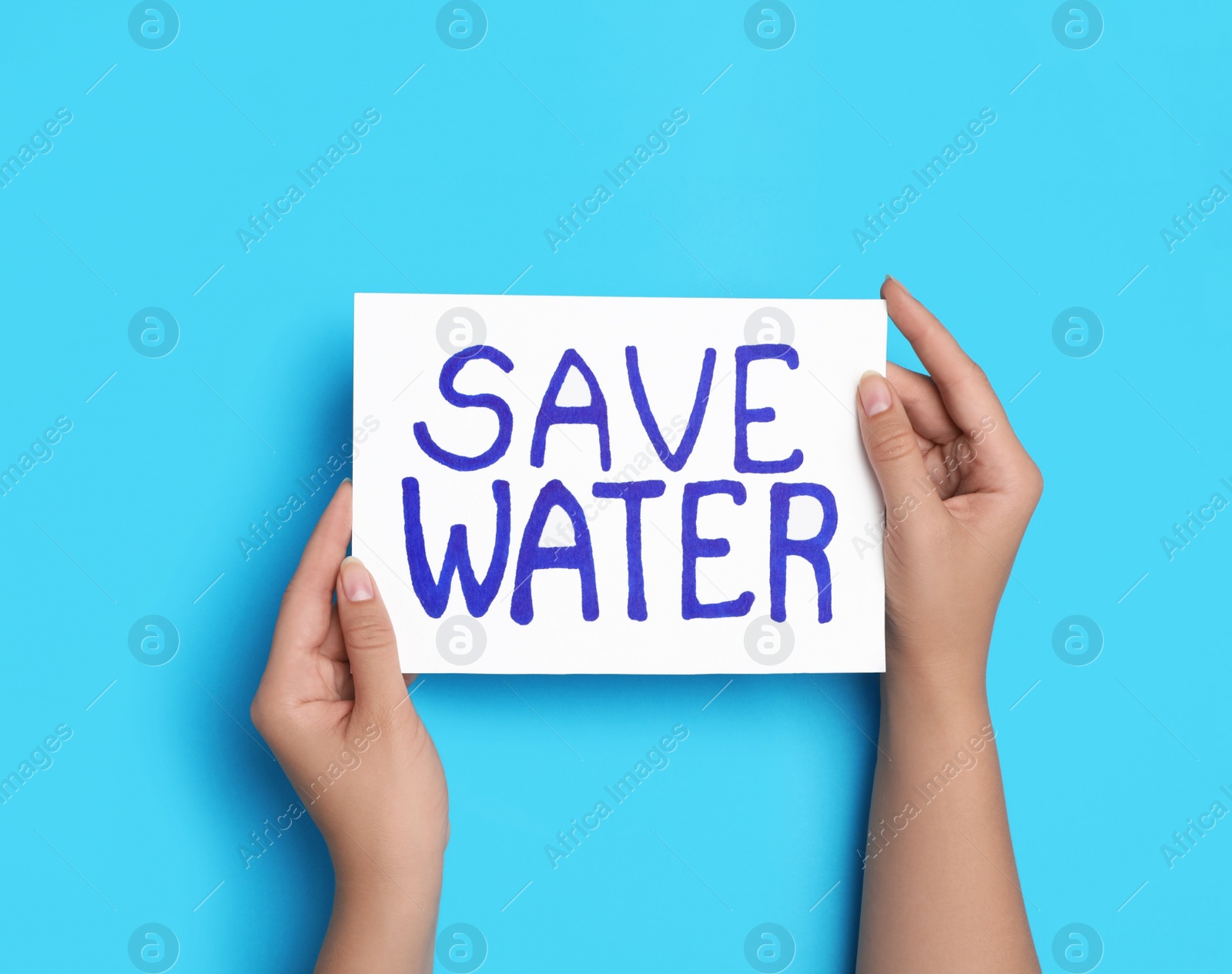 Photo of Woman holding card with words Save Water on light blue background, top view