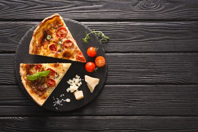 Photo of Pieces of delicious homemade quiche with prosciutto and ingredients on black wooden table, flat lay. Space for text