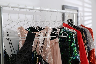 Photo of Rack with collection of beautiful festive clothes indoors, closeup