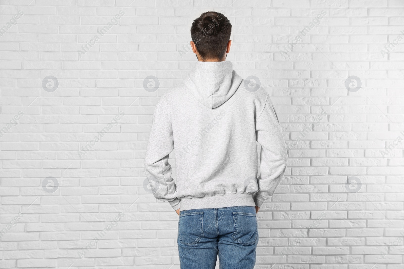 Photo of Young man in sweater at brick wall. Mock up for design