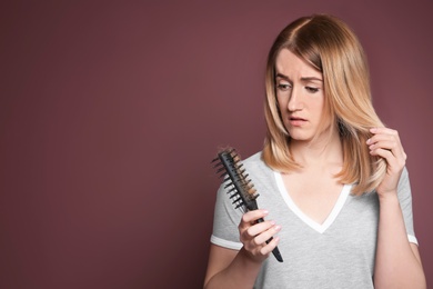 Young woman with hair loss problem on color background