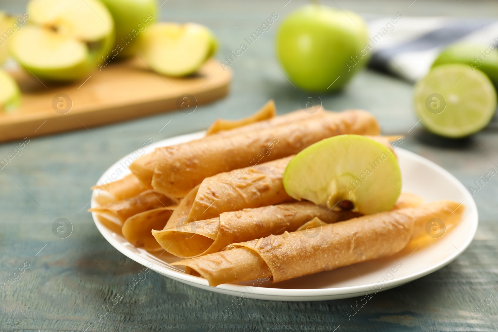 Photo of Composition with delicious fruit leather rolls and apple on blue wooden table