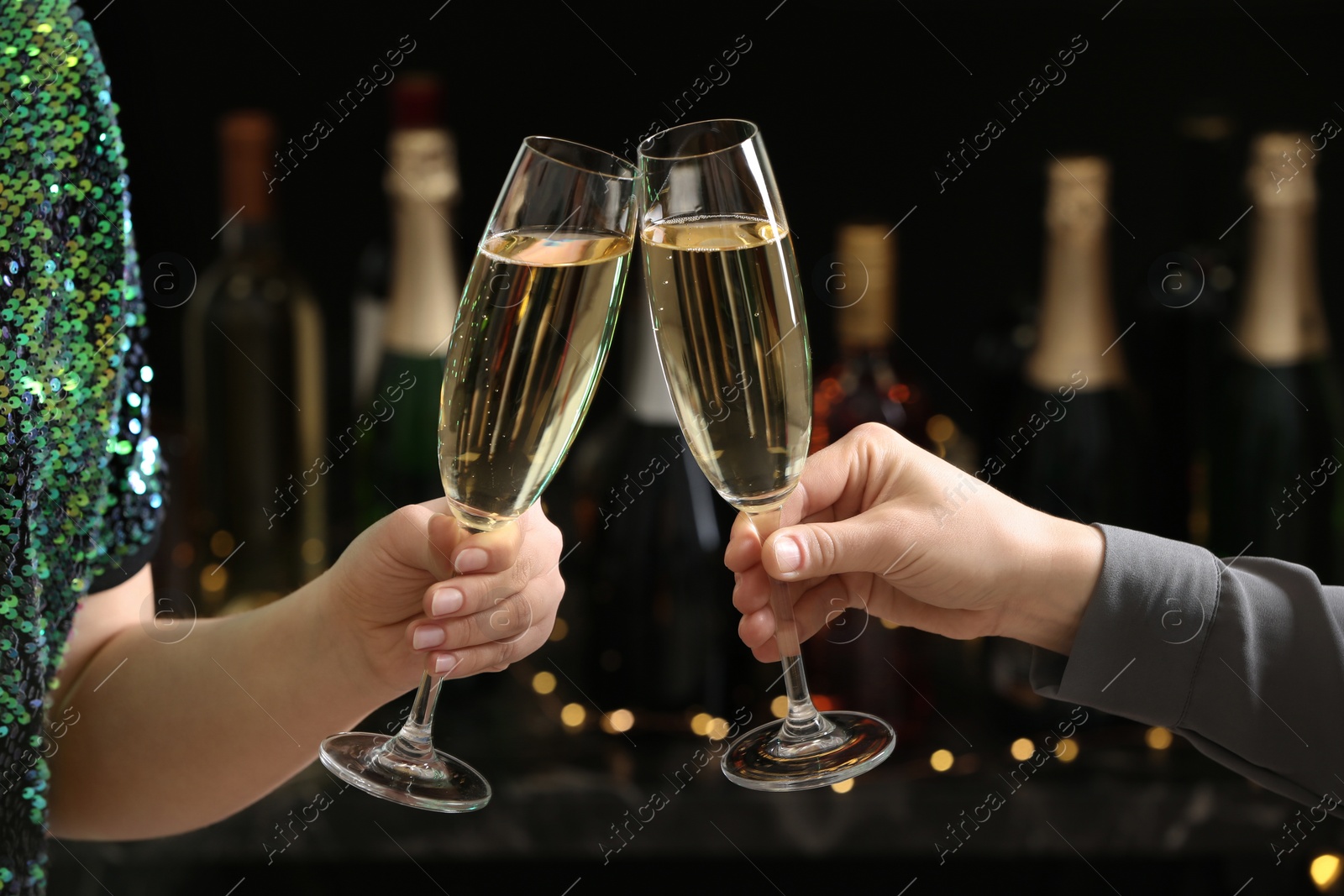 Photo of People clinking glasses of champagne on blurred background, closeup