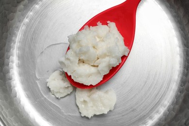 Photo of Frying pan with coconut oil and spoon, top view