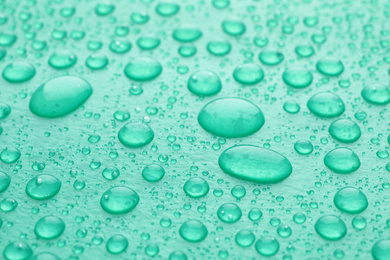 Photo of Water drops on turquoise background, closeup view