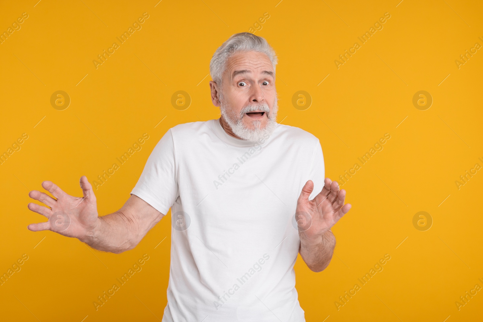 Photo of Portrait of surprised senior man on yellow background