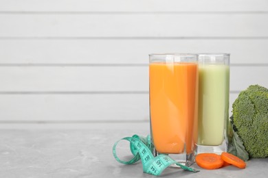 Photo of Tasty shakes, vegetables and measuring tape on light gray marble table, space for text. Weight loss