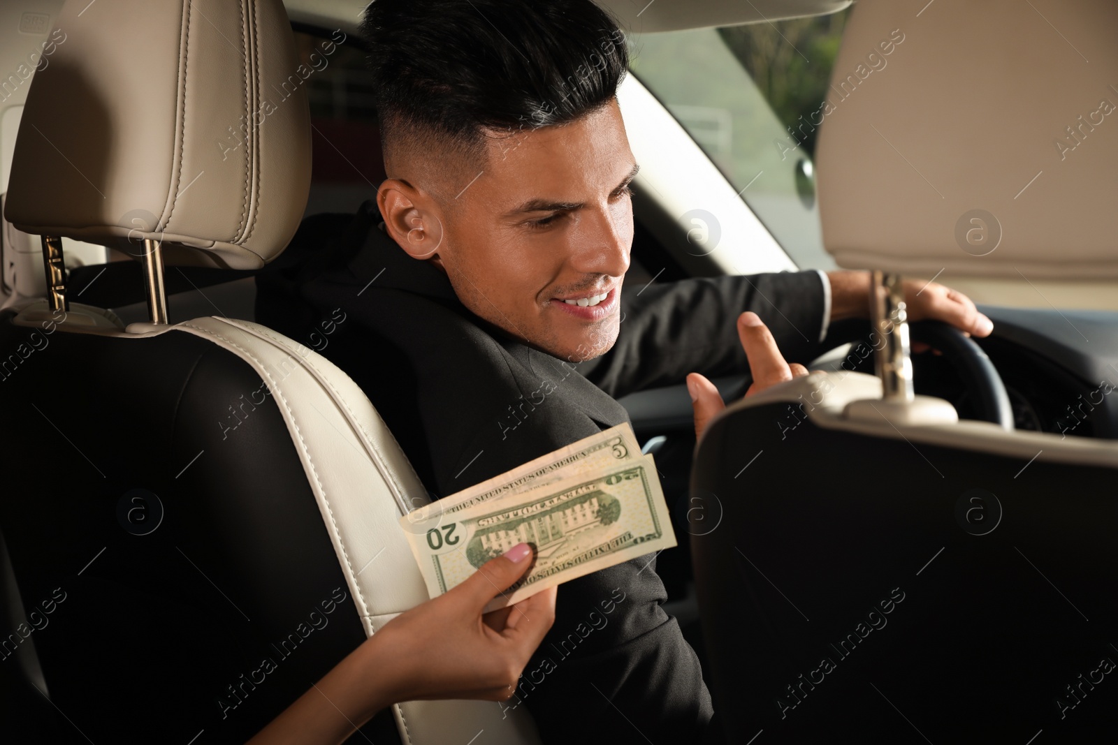 Photo of Young woman giving money taxi driver in modern car, closeup