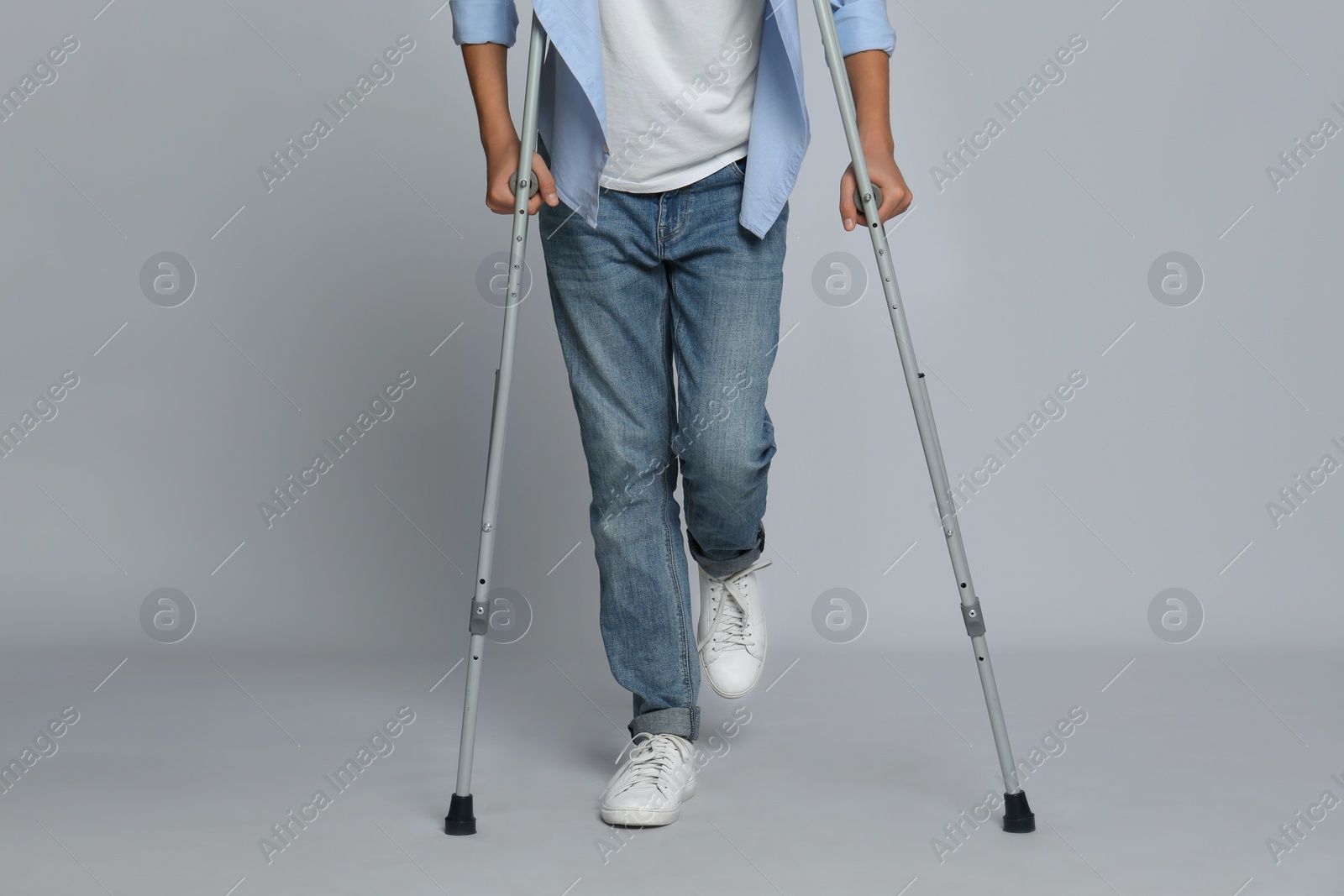 Photo of Man with injured leg using crutches on grey background, closeup