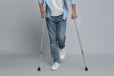 Photo of Man with injured leg using crutches on grey background, closeup