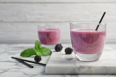 Photo of Glass with tasty blackberry yogurt smoothie on table