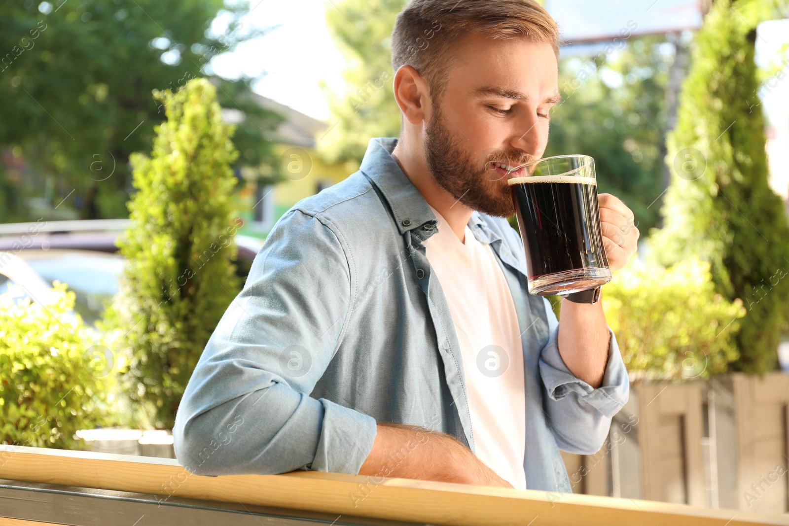 Photo of Handsome man with cold kvass outdoors. Traditional Russian summer drink