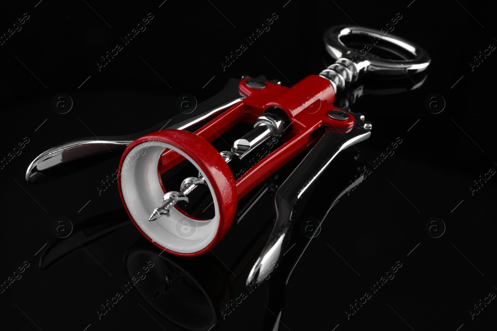 Photo of One wing corkscrew on dark mirror table, closeup