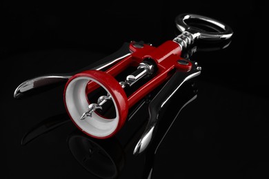 Photo of One wing corkscrew on dark mirror table, closeup