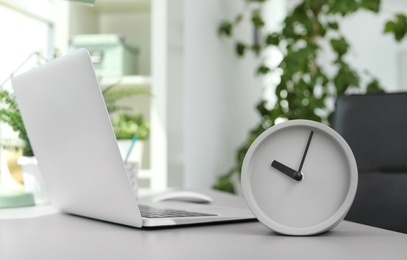 Photo of Analog alarm clock on table in office. Time to work