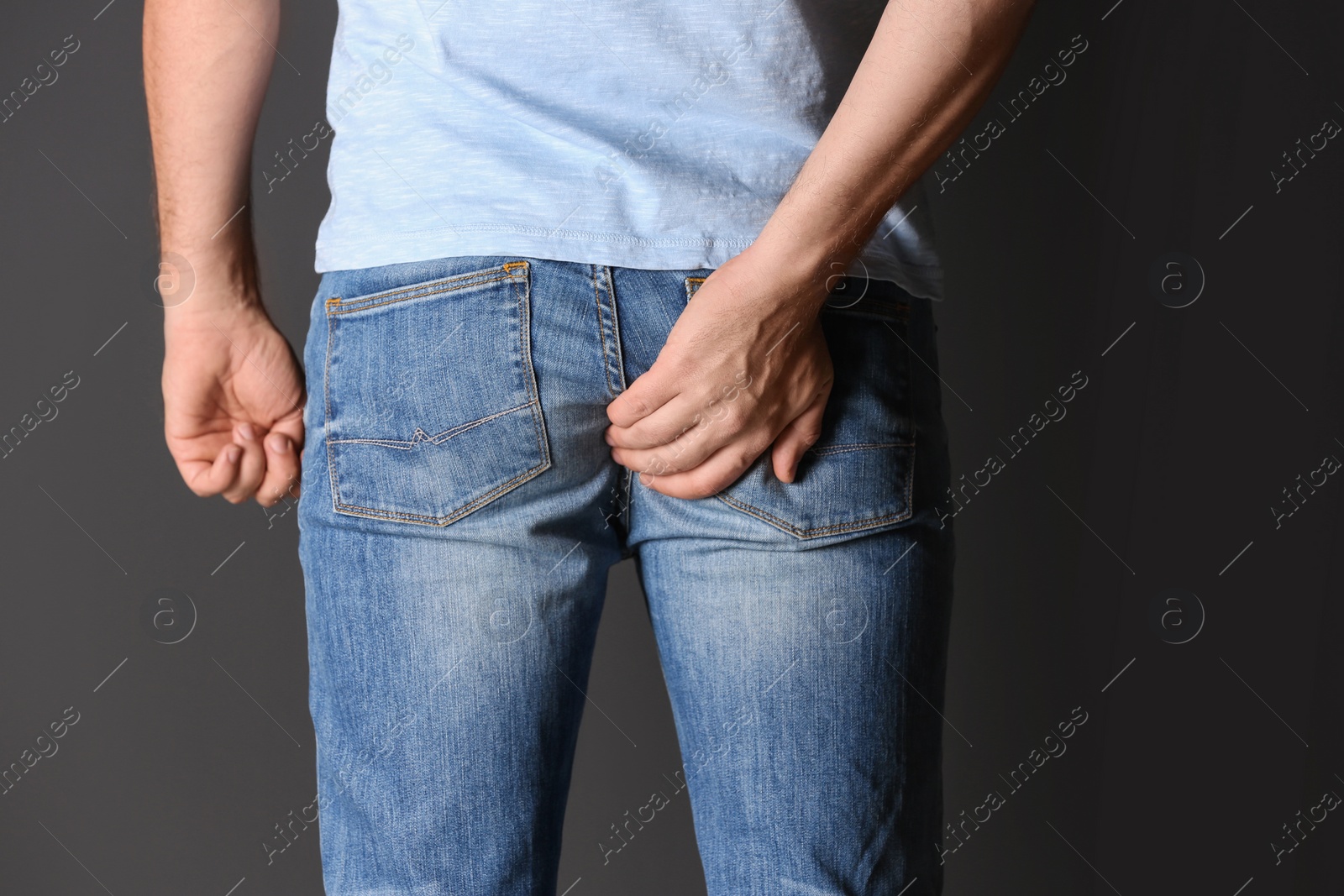 Photo of Man suffering from hemorrhoid on black background, closeup