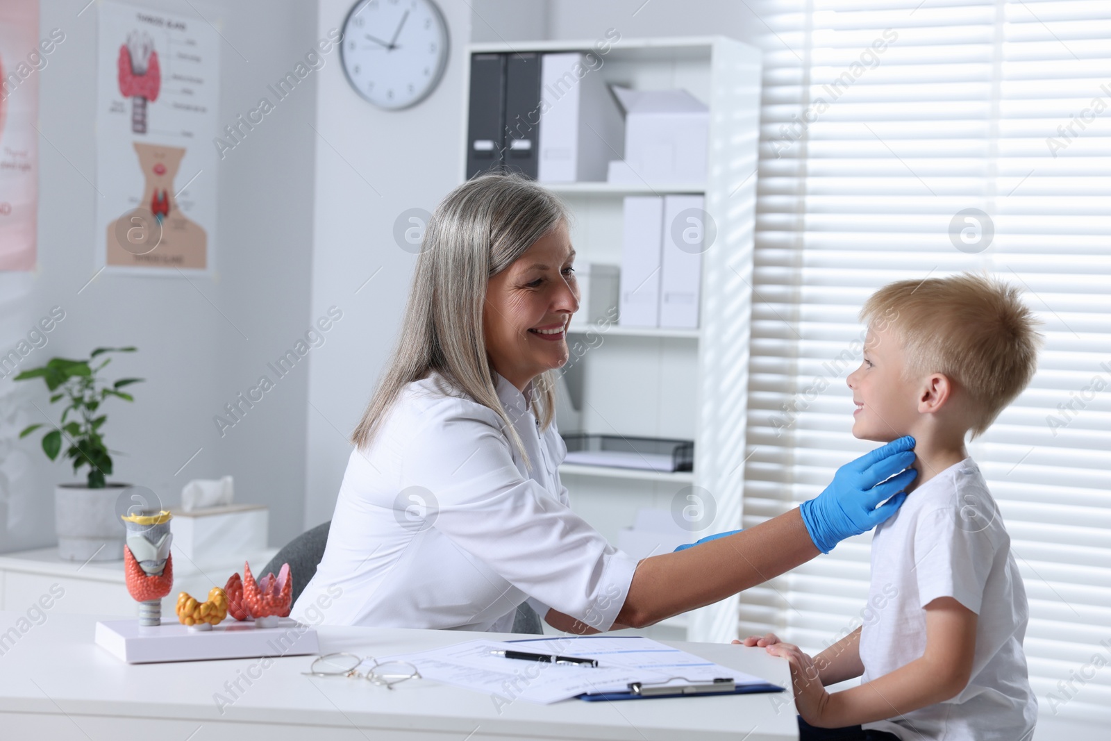 Photo of Endocrinologist examining boy's thyroid gland at table in hospital