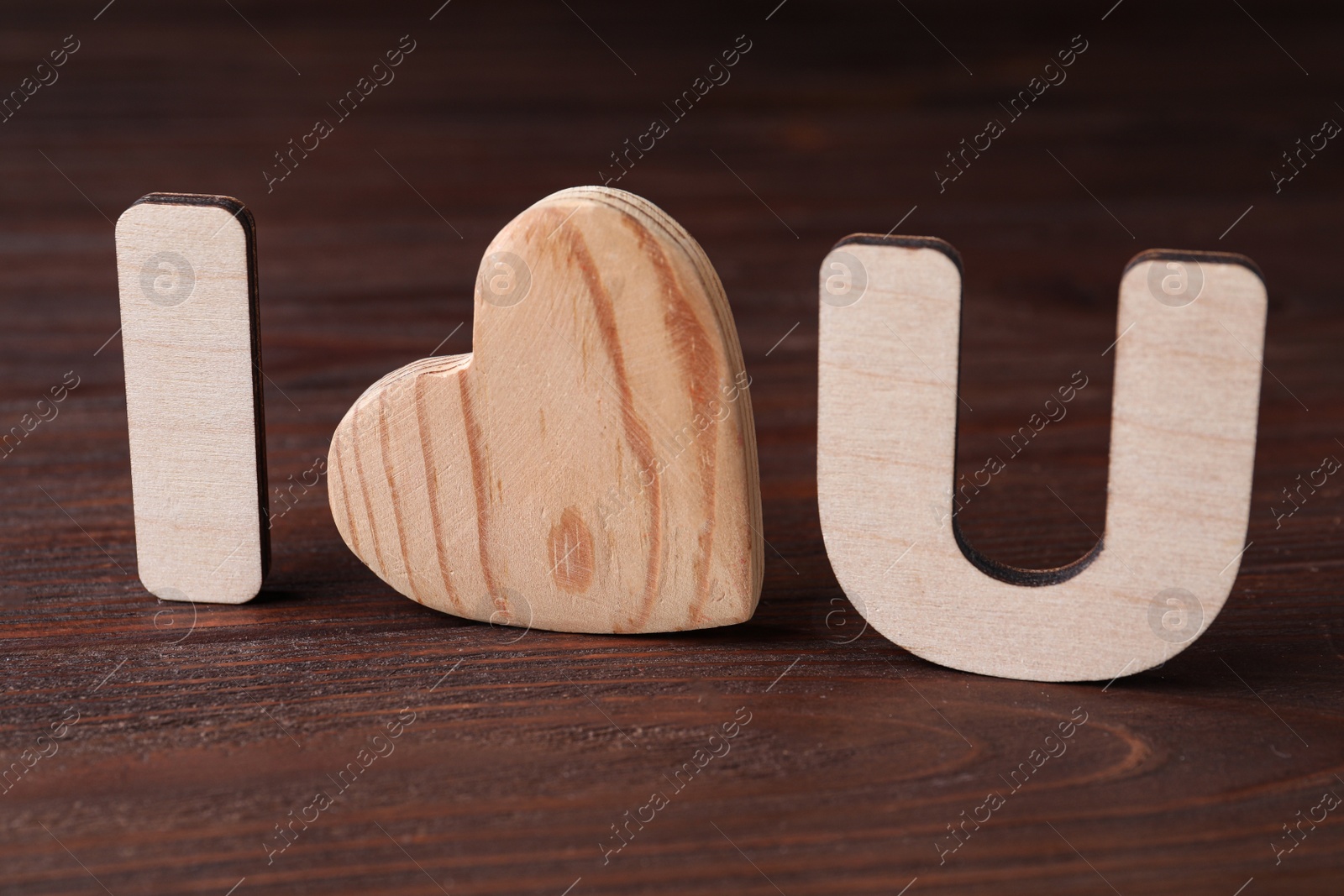 Photo of Phrase I Love You made of wooden letters and heart on table