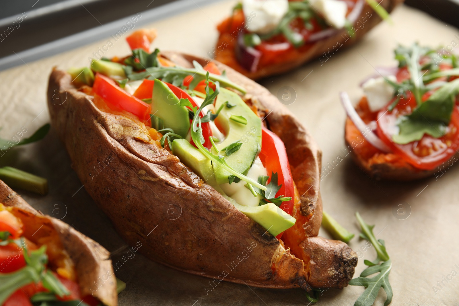 Photo of Delicious stuffed sweet potatoes on parchment, closeup