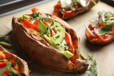 Delicious stuffed sweet potatoes on parchment, closeup