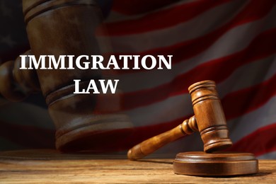 Immigration law. Judge's gavel on wooden table against American flag in darkness