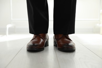 Photo of Groom wearing elegant wedding shoes indoors, closeup