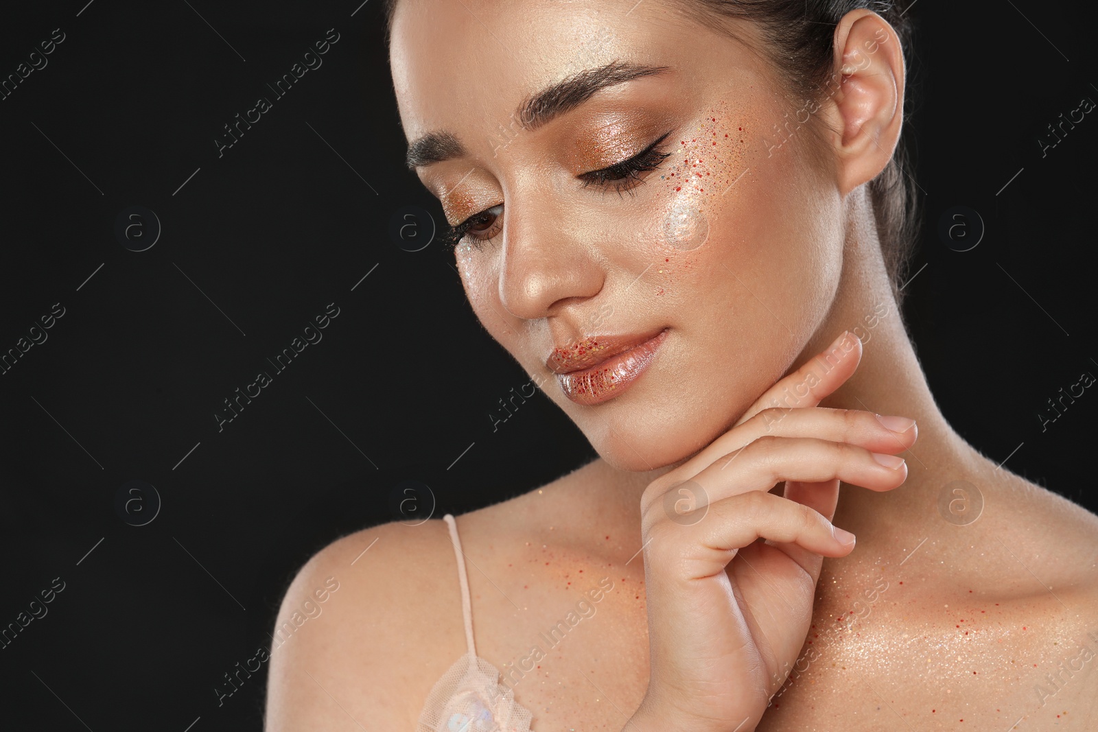 Photo of Beautiful young woman with glitter makeup on black background