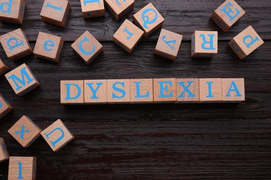 Photo of Cubes with word Dyslexia on wooden background, flat lay