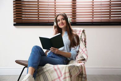 Photo of Woman listening to audiobook in chair at home