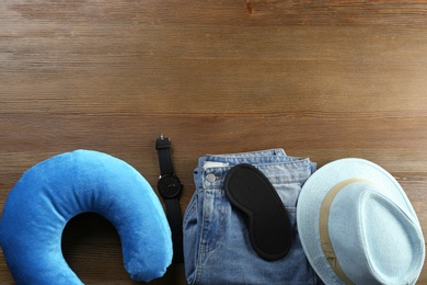 Photo of Flat lay composition with travel pillow and tourist stuff on wooden background. Space for text