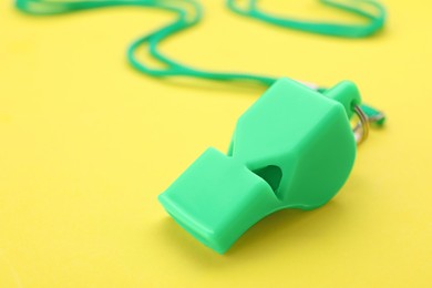 Photo of One green whistle with cord on yellow background, closeup
