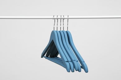 Photo of Empty clothes hangers on metal rail against light background