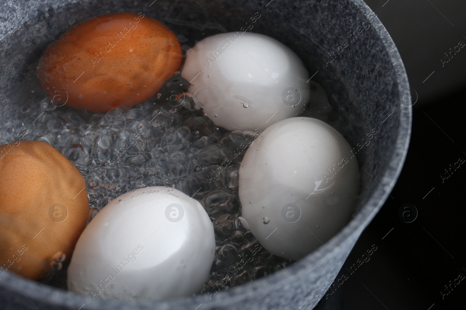 Photo of Chicken eggs boiling in saucepan, closeup view