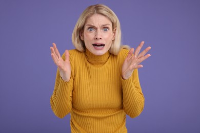 Photo of Portrait of surprised woman on violet background