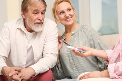 Photo of Woman showing her parents pregnancy test at home. Grandparents' reaction to future grandson