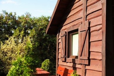 Photo of Exteriorcozy wooden house surrounded by lush nature on sunny day, closeup