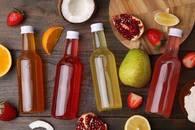 Delicious kombucha in glass bottles, fresh fruits and coconut on wooden table, flat lay