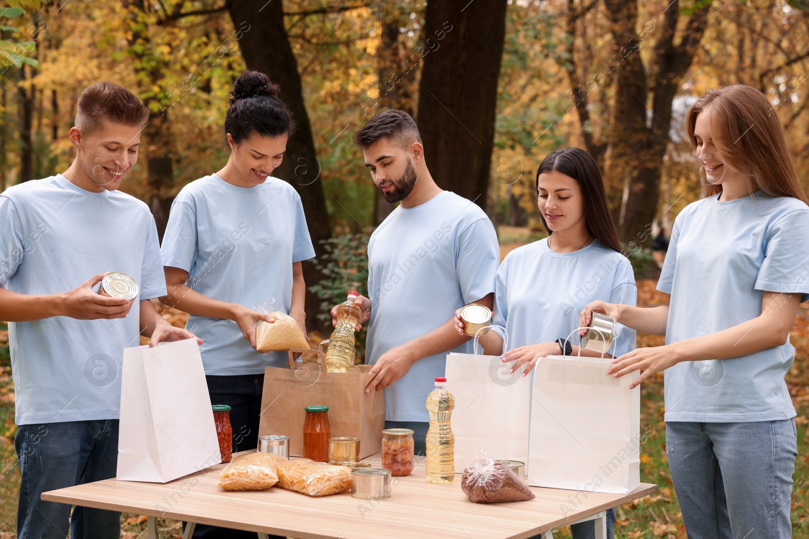 Photo of Group of volunteers packing food products at table in park