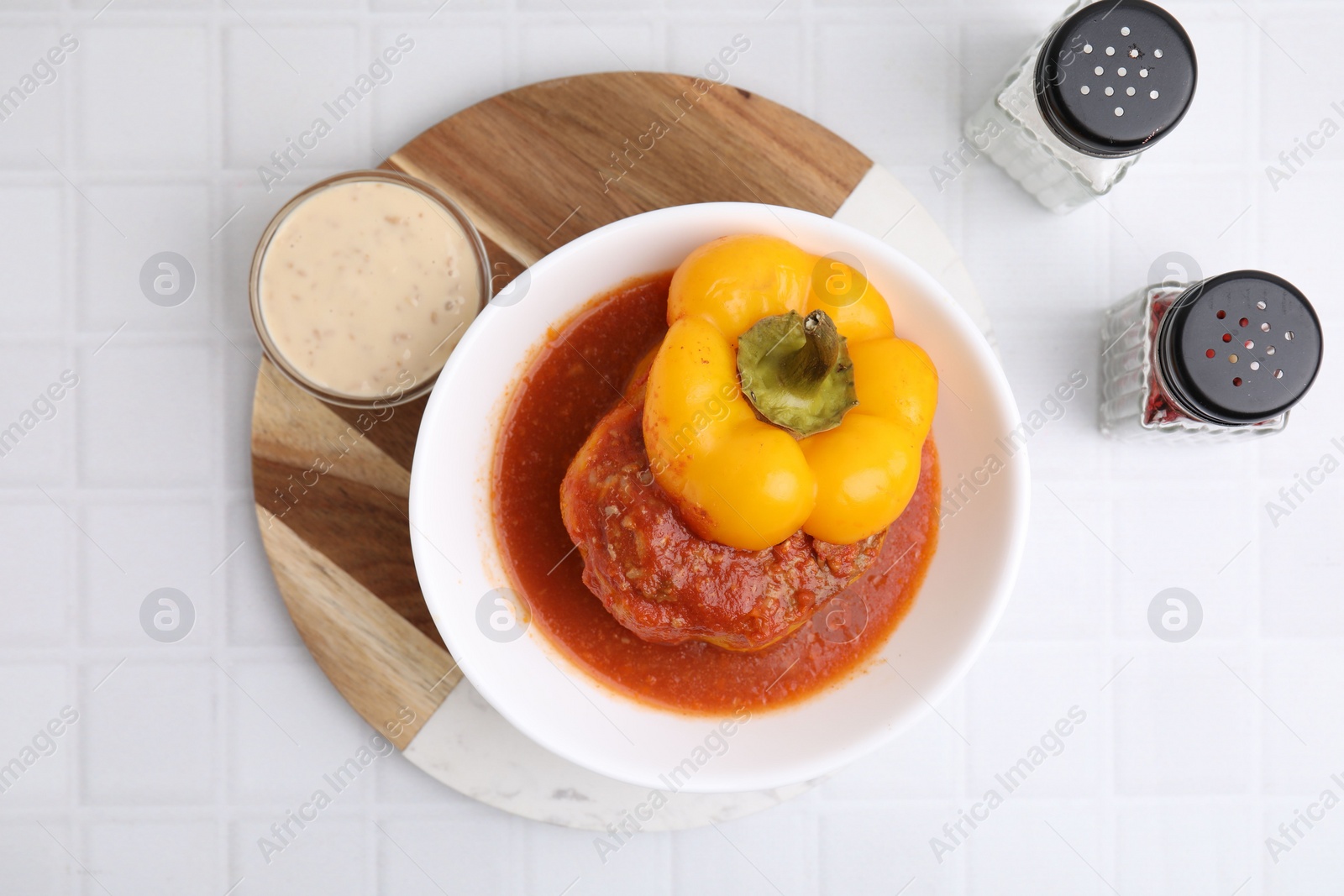 Photo of Delicious stuffed bell pepper served on white tiled table, flat lay